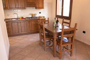 Une cuisine avec des meubles de rangement en bois, un pare-feu en carreaux, une table à manger avec des chaises et une fenêtre.