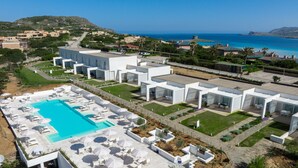 A modern hotel with a large swimming pool, outdoor seating, and a view of the ocean. - Capo Falcone B. Premium, Stintino, Italy (Stintino)
