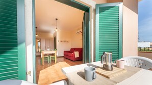 Un espacio habitable de planta abierta con una mesa de comedor, un sofá rojo, y una cocina visible a través de la puerta abierta.