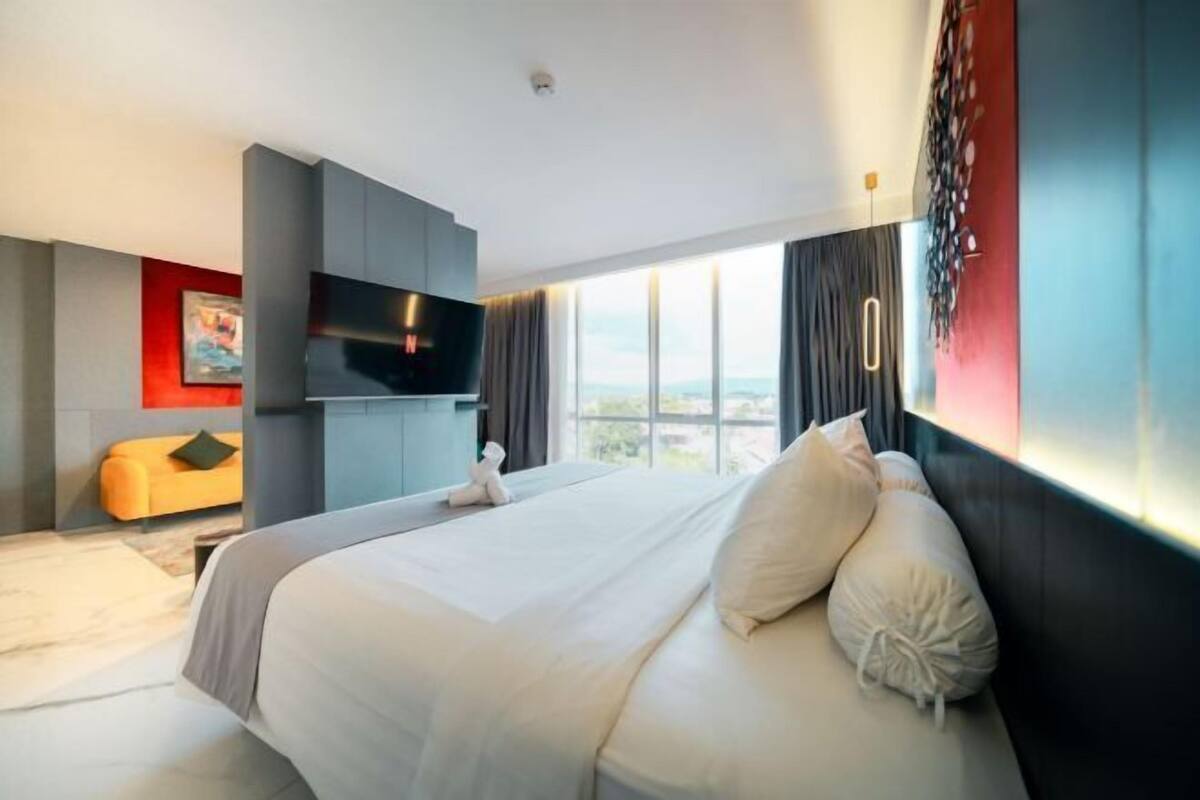 Une chambre d’hôtel moderne dotée d’un grand lit, d’une télévision à écran plat, d’un canapé et offrant une vue sur la ville.