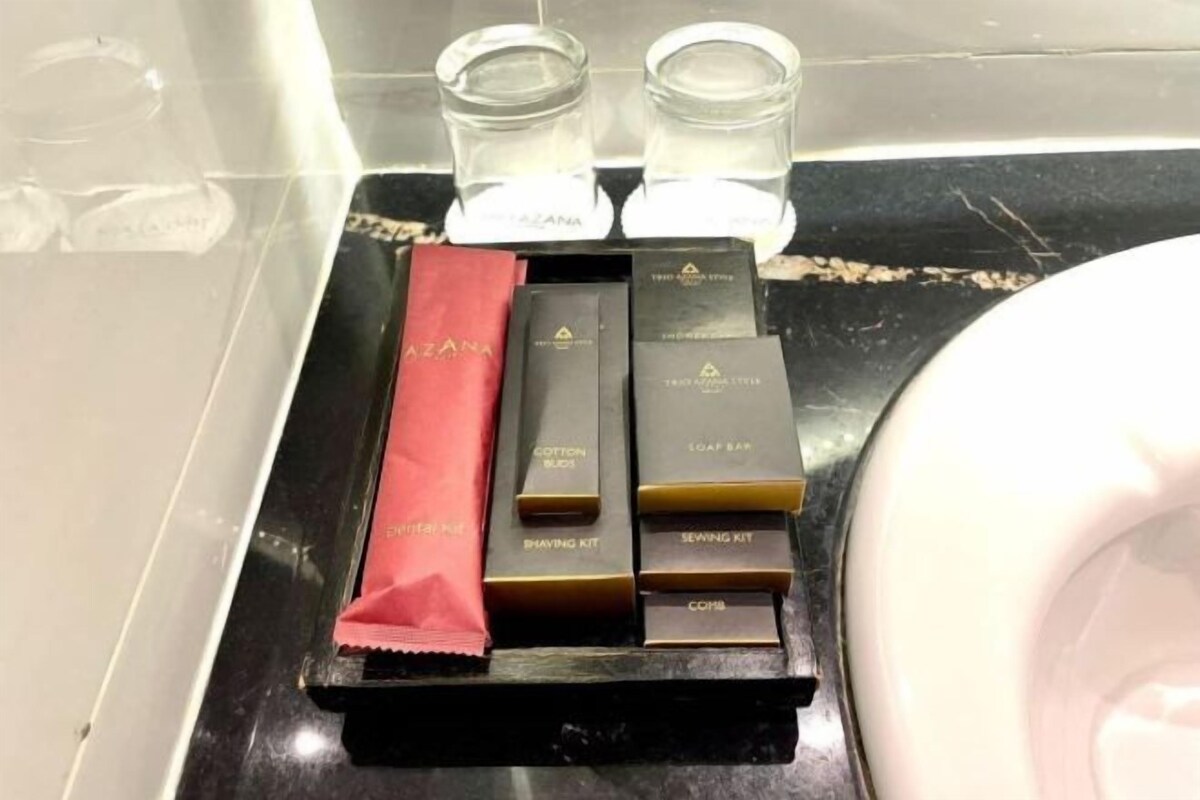 Una encimera de baño con una bandeja negra que contiene varios artículos de aseo personal, como bastoncillos de algodón, un kit de afeitado y un kit de costura.