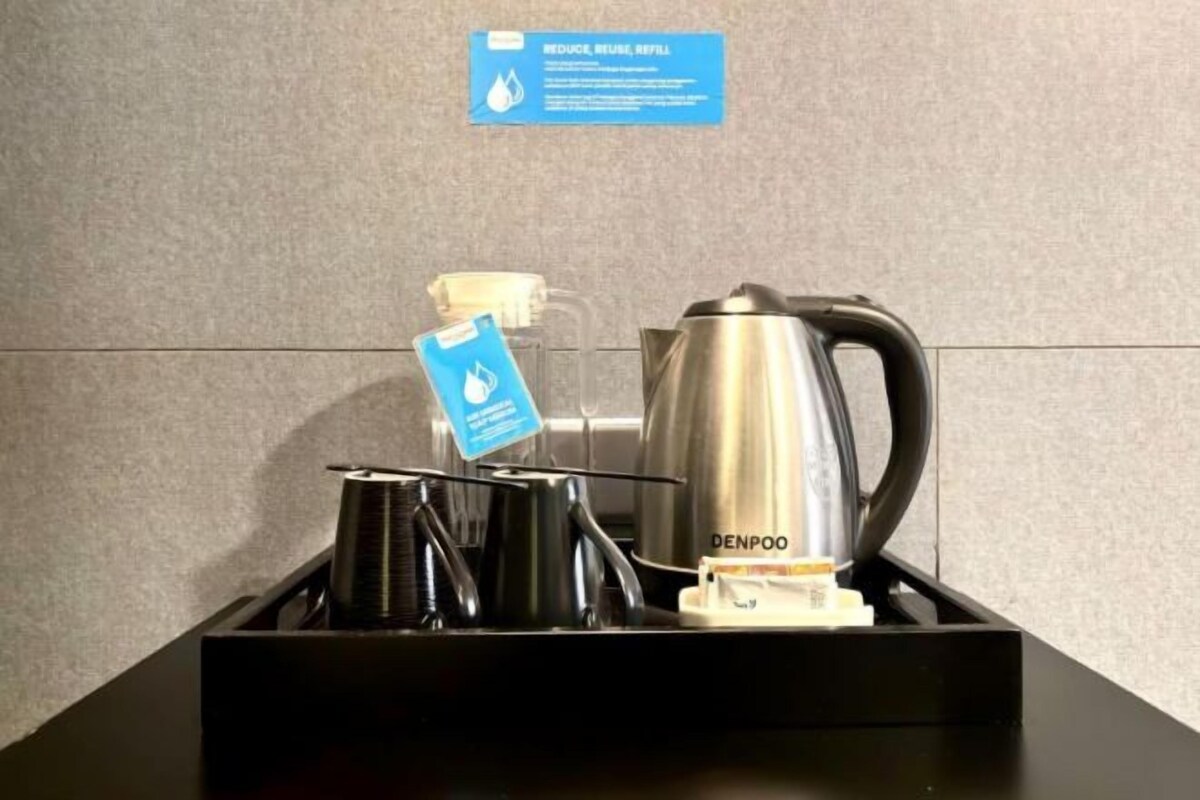 A hotel room's minibar with a coffee maker, tea pot, and a water bottle.