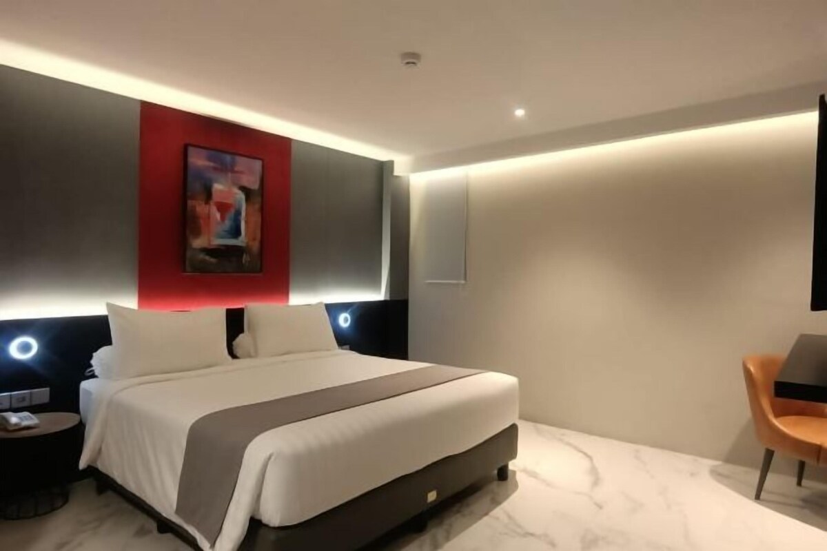 Una habitación de hotel moderna con una cama grande, un escritorio y una silla.
