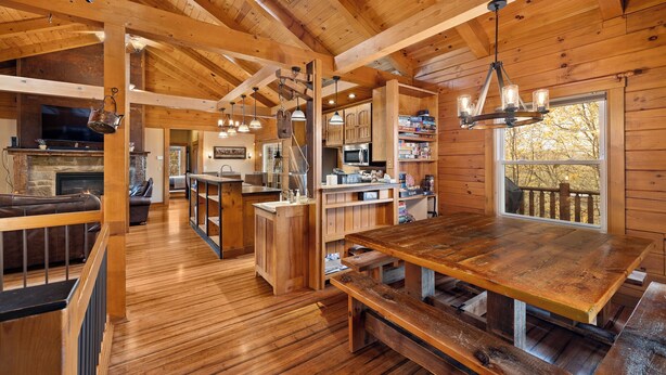 Un intérieur de chalet en bois spacieux, comprenant une grande table à manger, un coin cuisine et un espace salon confortable.