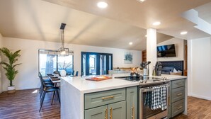 A modern kitchen with a large island, built-in oven, and a dining area with bar stools. - Yosemite zen, Pool, Hot tub, Private suite and Views! (oakhurst)