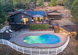 Una casa amb piscina, panells solars i terrassa amb mobiliari d'exterior.