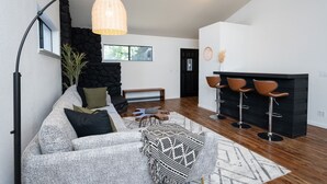 A modern living room with a grey sofa, a black fireplace, and a bar area with stools. - Yosemite zen, Pool, Hot tub, Private suite and Views! (oakhurst)