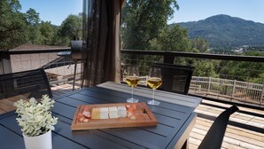A wooden deck with a table set for two, featuring a small plant, a wooden board with food, and two glasses of wine. - Yosemite zen, Pool, Hot tub, Private suite and Views! (oakhurst)
