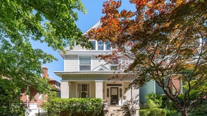 A two-story house with a front porch, a brick chimney, and a well-maintained garden.