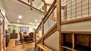 A wooden staircase with a grid design, a dining area with a table and chairs, and a view of the kitchen area.