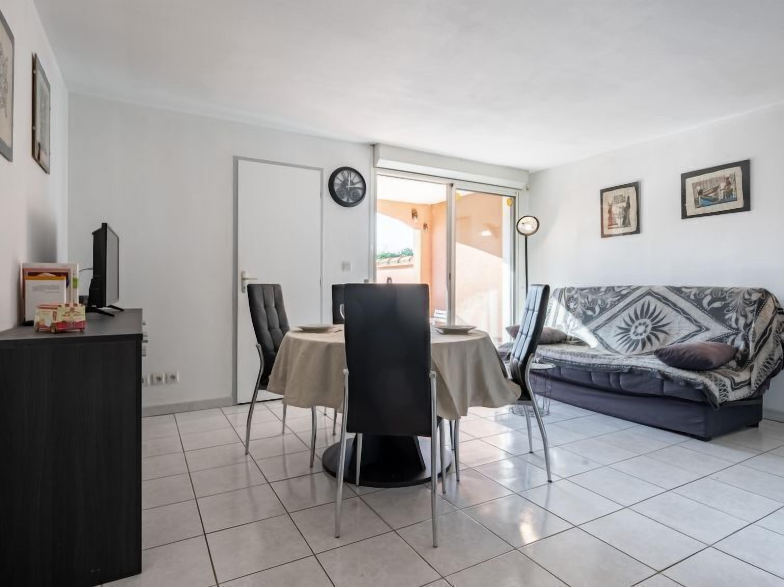 A modern living room with a dining area, a sofa, and a TV on a cabinet.