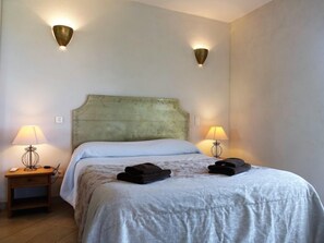 A bedroom with a bed, two wall-mounted lamps, and a nightstand with a lamp. - Villa Orizonte by Interhome (Solenzara)