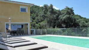 A pool area with lounge chairs and a building with a yellow facade.