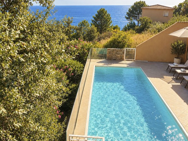 A rectangular swimming pool with clear blue water, surrounded by a tiled deck.
