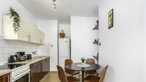 Une cuisine compacte avec un coin repas, comprenant une cuisinière, un four, un évier et un petit réfrigérateur.