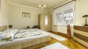 Une chambre à coucher comprenant un lit, une armoire, un bureau, une chaise, une lampe et une fenêtre avec des rideaux.