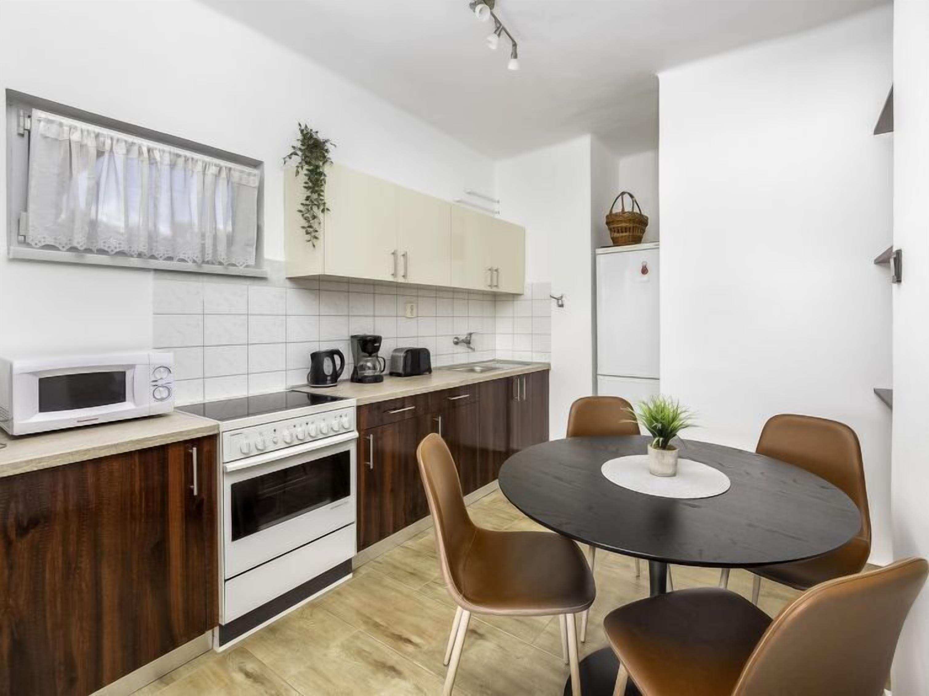 A compact kitchen with white cabinets, a microwave, a stove, and a dining area with a round table and chairs.