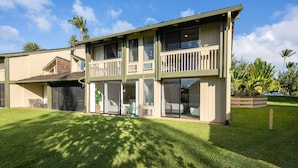 A two-story building with a balcony, large windows, and a well-maintained lawn. - Hale Kuilima: Condo on the Golf Course at Turtle Bay (Kahuku)