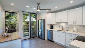 A modern kitchen with white cabinets, stainless steel appliances, and a wooden countertop. - Hale Kuilima: Condo on the Golf Course at Turtle Bay (Kahuku)