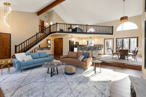 A spacious living room with a high ceiling, a staircase, and a dining area. - 5BR Spacious Poconos Home! 20 Min to Ski Resorts! (East Stroudsburg)