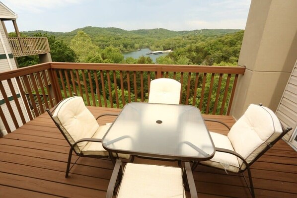 Enjoy the serene view from this balcony with a glass-top table and two cushioned chairs.