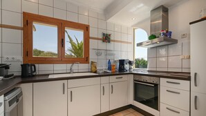 A modern kitchen with white cabinets, a wooden window, a stainless steel range hood, and a dishwasher. - Puravida - Javea, Costa Blanca (Javea)