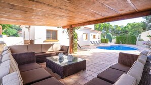 An outdoor patio with wicker furniture, a glass-top table, and a swimming pool in the background. - Vacation home Johlim by Interhome (Moraira)