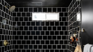 Un baño con baldosas blanco y negro a cuadros, un lavabo blanco y un perchero con un bolso.