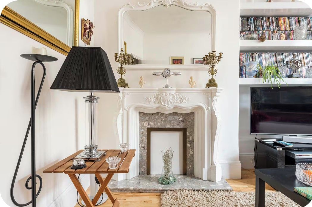 A living room with a fireplace, a television, a bookshelf, and a lamp.
