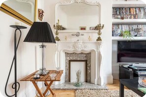 Ein Wohnzimmer mit Kamin, Fernseher, Bücherregal und Lampe.