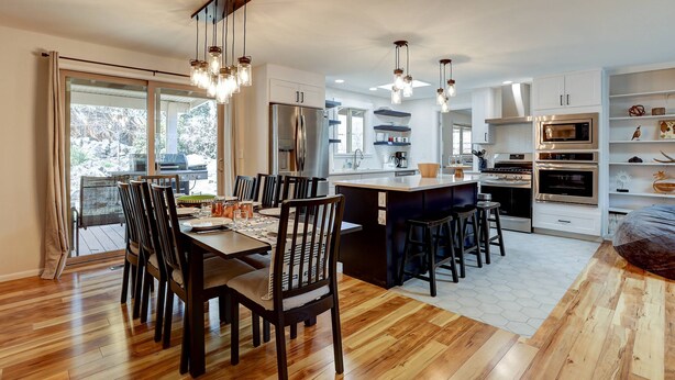 A modern kitchen with a central island, stainless steel appliances, and a dining area with wooden chairs. - Wonderful Updated Single Level Retreat w/ Backyard Oasis, Pet Friendly, A/C, Hot Tub, Private Patio (Bend)