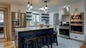 A modern kitchen with a central island, stainless steel appliances, and bar stools. - Wonderful Updated Single Level Retreat w/ Backyard Oasis, Pet Friendly, A/C, Hot Tub, Private Patio (Bend)