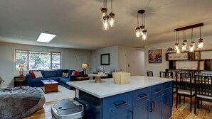 A modern kitchen with blue cabinets, a central island, and pendant lighting. - Wonderful Updated Single Level Retreat w/ Backyard Oasis, Pet Friendly, A/C, Hot Tub, Private Patio (Bend)