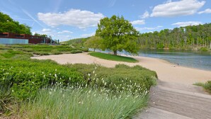 A riverside park with a wooden boardwalk, a sandy beach, and a large tree. - Ferienhaus Bude 87 by Interhome (Bad Arolsen)