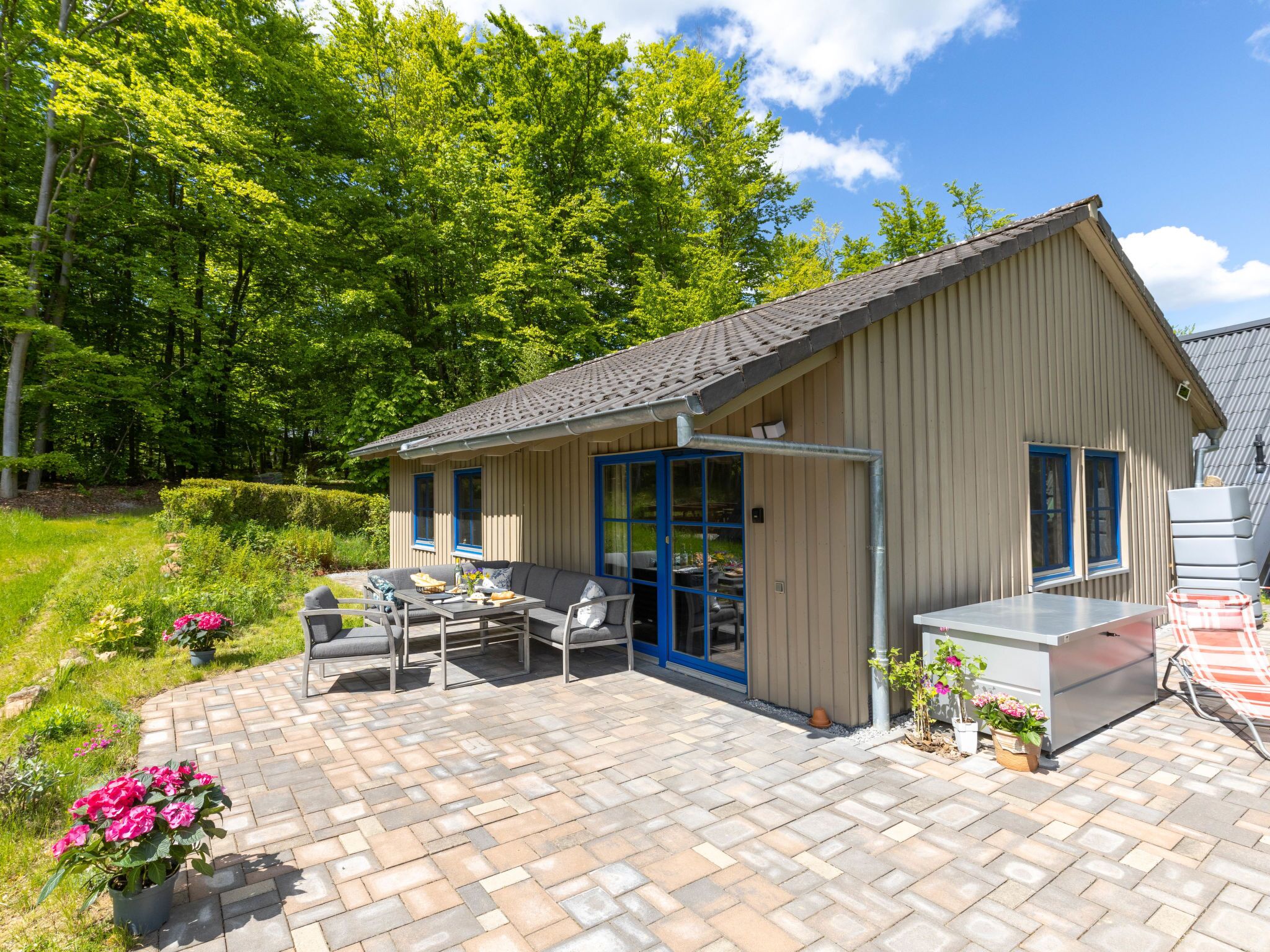 A wooden cabin with a patio area, outdoor furniture, and potted plants.