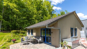 A wooden cabin with a patio area, outdoor furniture, and potted plants. - Ferienhaus Bude 87 by Interhome (Bad Arolsen)