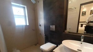 A bathroom with a toilet, sink, and a window. - Yuvraj Palace Inn (Mysore)