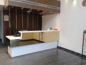 A reception desk with a modern design, featuring a white counter and a recessed area. - Yuvraj Palace Inn (Mysore)