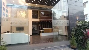 A modern hotel entrance with a glass facade, a reception desk, and a staircase leading to the lobby. - Yuvraj Palace Inn (Mysore)