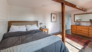 A bedroom with a bed, bedside table, dresser, mirror, and a rug.
