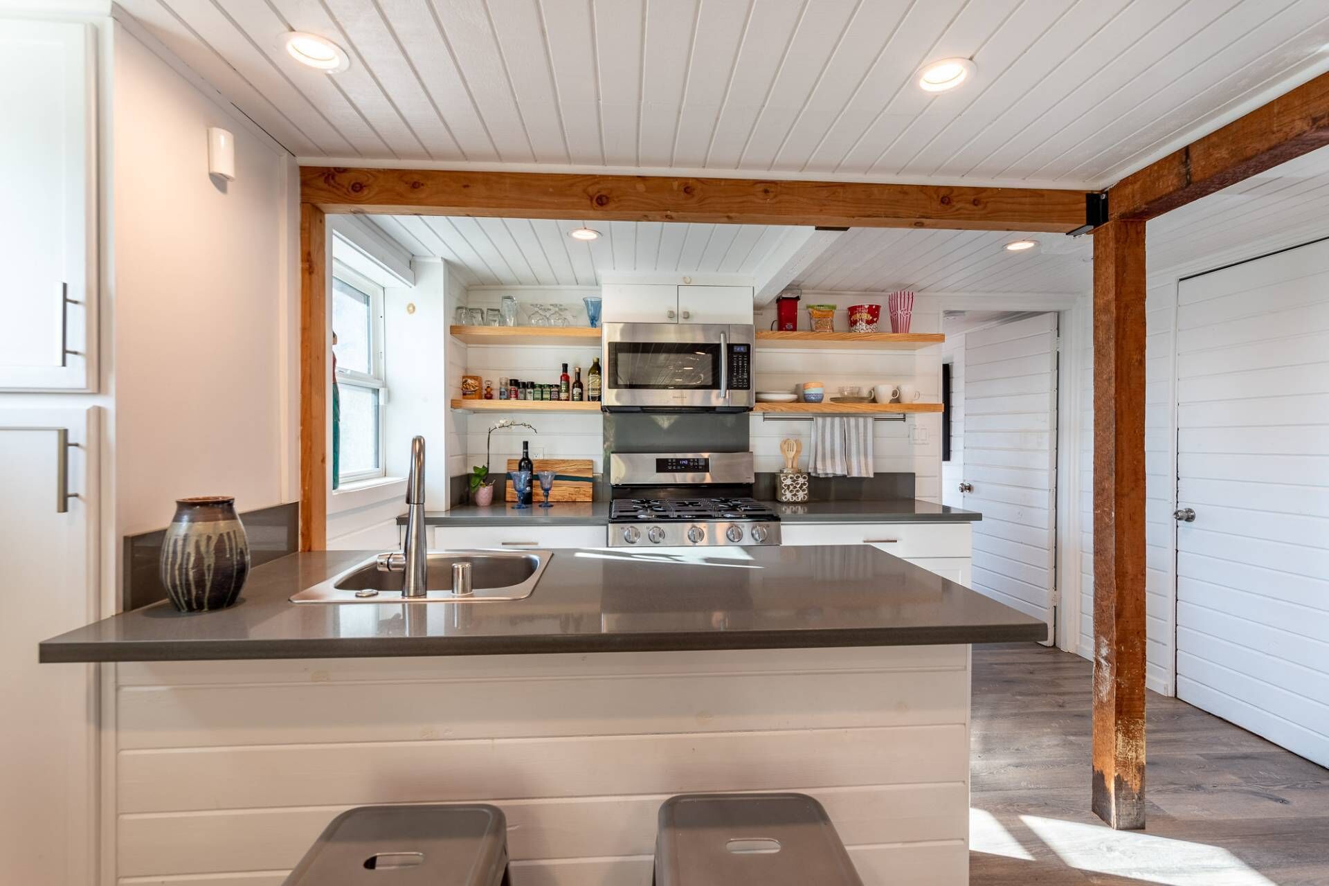 A modern kitchen with a central island, stainless steel appliances, and wooden beams on the ceiling.