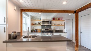 A modern kitchen with a central island, stainless steel appliances, and wooden beams on the ceiling.