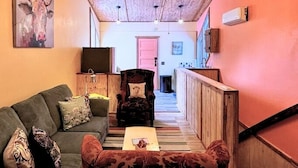 A cozy living area with a green sofa, a patterned armchair, and a wooden ceiling. - Secluded Estate Sleeps 8 with 1 acre fishing pond  (Mount Pleasant)