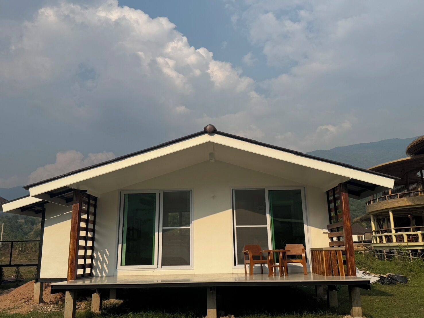 A modern house with a flat roof, large windows, and a balcony with wooden furniture.