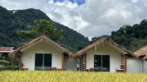 Two thatched-roof cottages with large windows, set in a rice field with a mountainous backdrop. - Sapan Dee View (Bo Kluea)