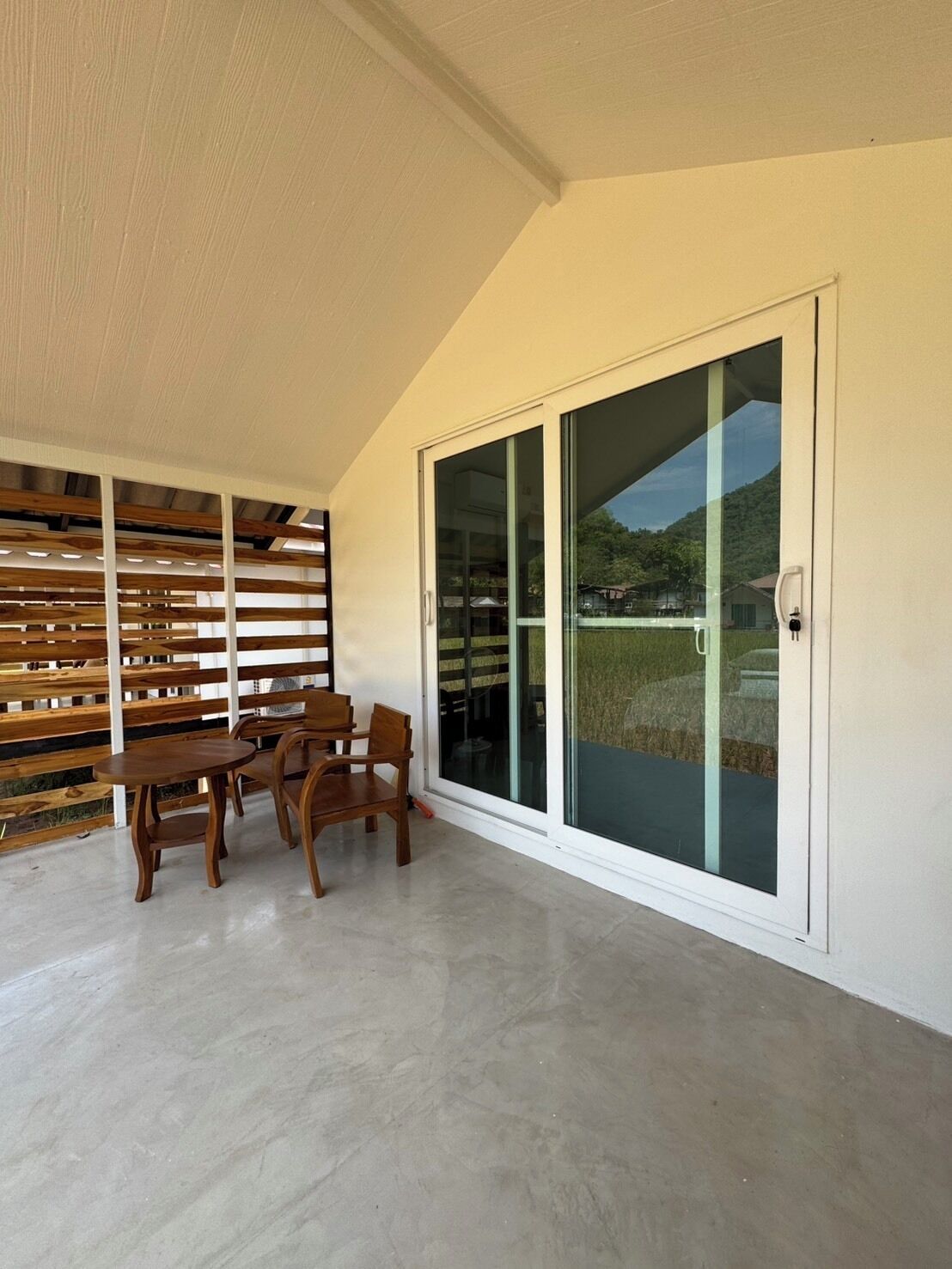 A room with a wooden table and chairs, a sliding glass door, and a slatted wooden wall.