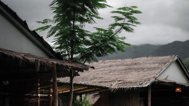 A rustic wooden structure with a thatched roof, a bamboo chair, and a table with a lamp. - Sapan Dee View (Bo Kluea)