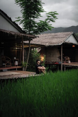 A rustic wooden structure with a thatched roof, a bamboo chair, and a table with a lamp. - Sapan Dee View (Bo Kluea)