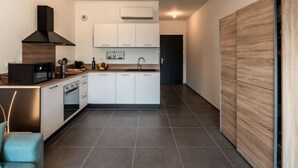 Una cocina moderna con armarios blancos, una campana extractora negra, un microondas y un lavamanos.