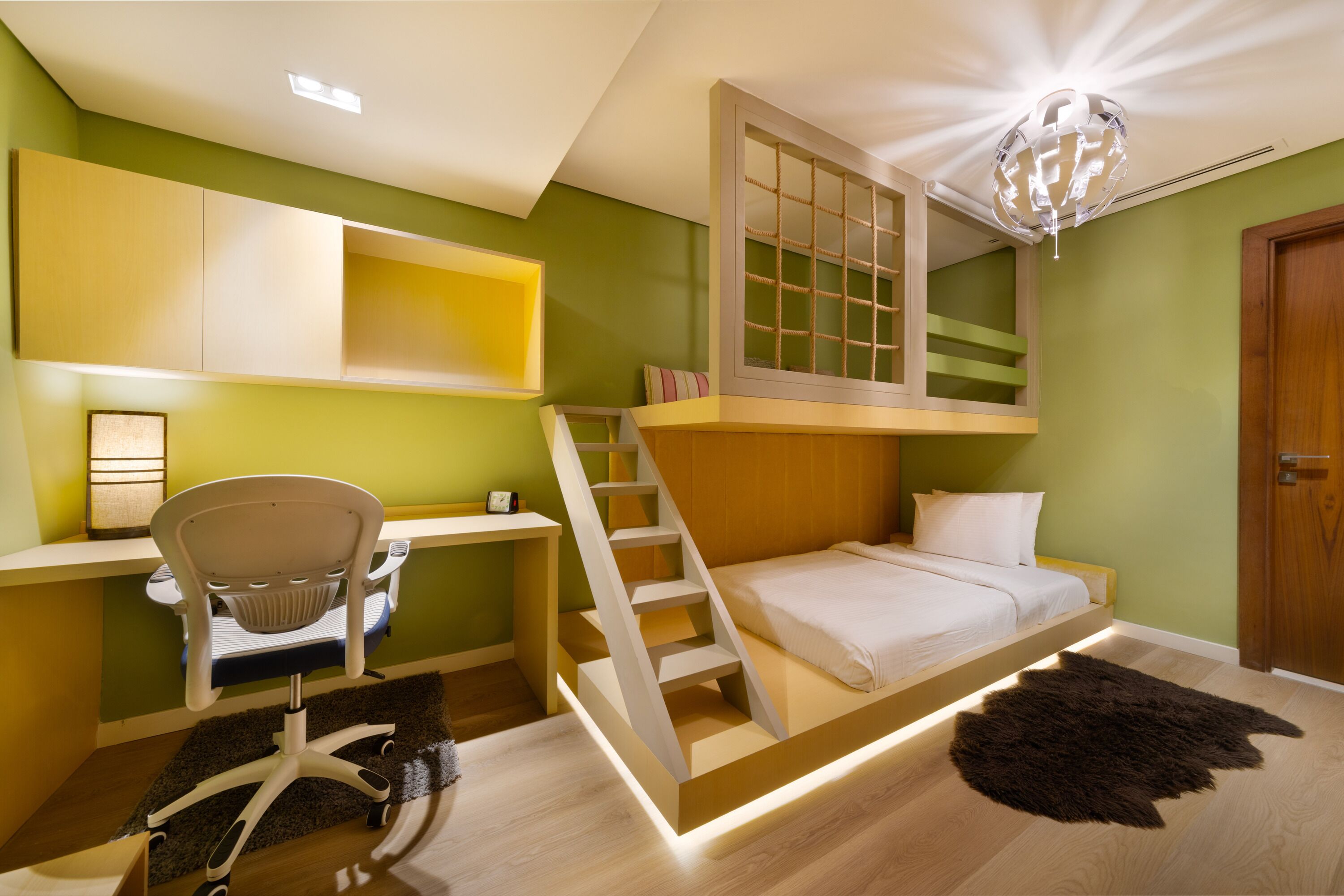 Une chambre avec un lit superposé, un bureau avec une chaise et un escalier.